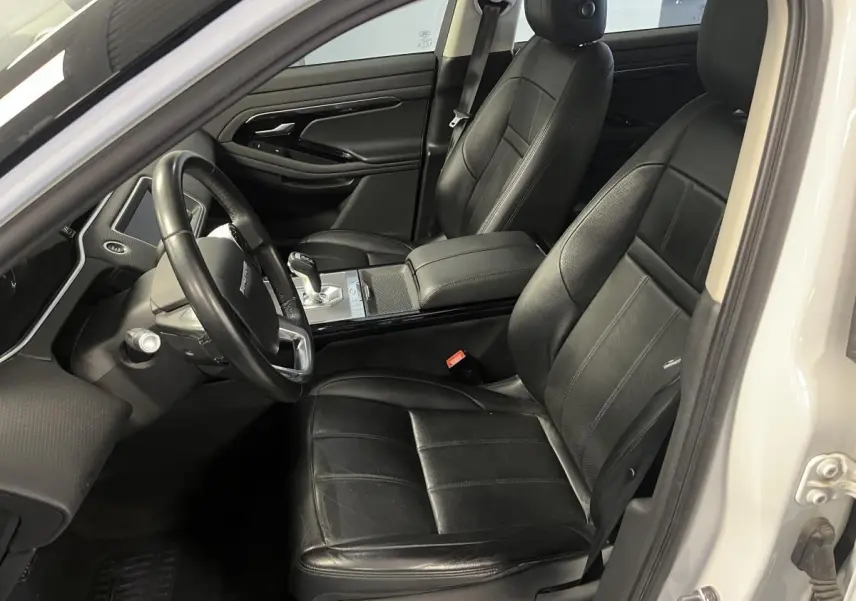 Vue intérieure côté conducteur du Range Rover Evoque blanc 2020, sièges cuir noirs et console centrale moderne.