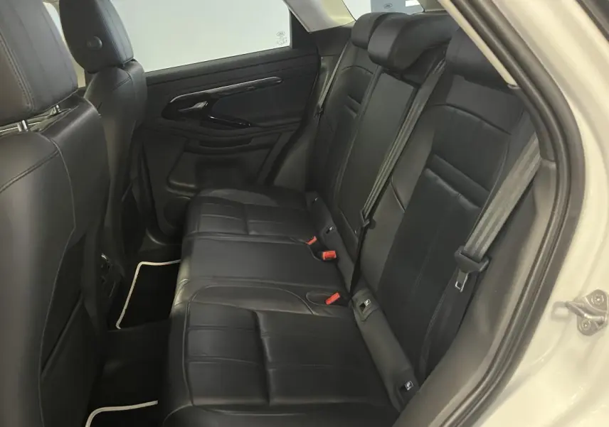 Vue intérieure côté droit des sièges arrière en cuir noir du Range Rover Evoque blanc 2020, avec ceintures et appuie-têtes visibles.