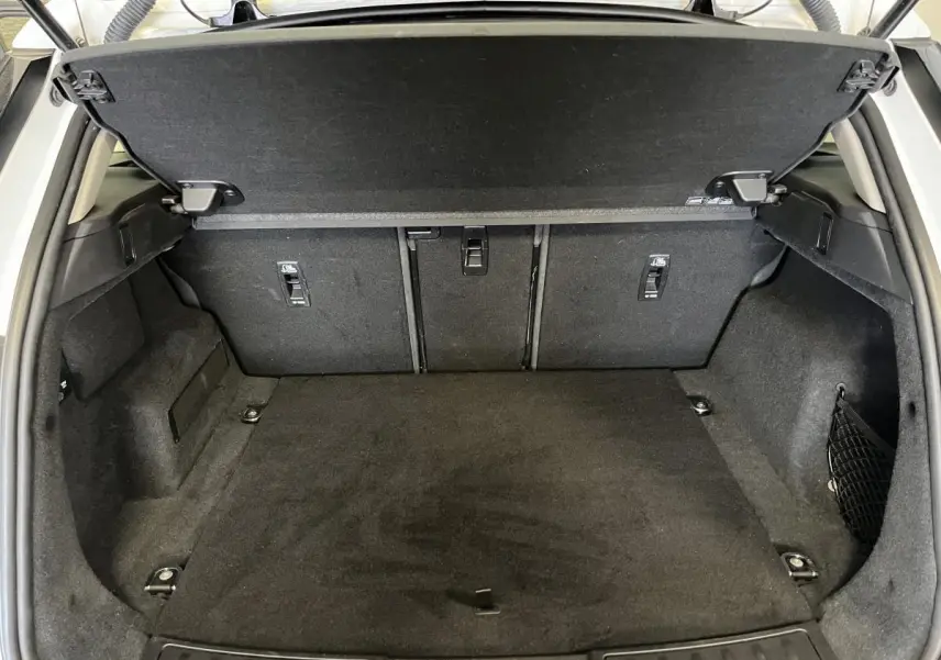 Coffre ouvert vu de l'arrière d'un Range Rover Evoque blanc, montrant l'espace de chargement et la tablette cache-bagages.