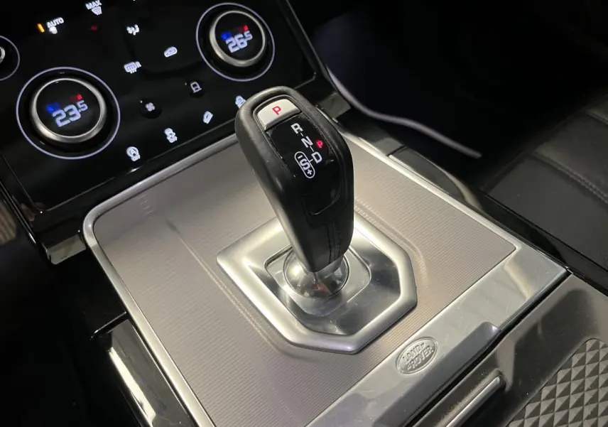 Le levier de vitesses automatique noir et argenté du Range Rover Evoque 2020 vu de près avec commandes de climatisation en arrière-plan.