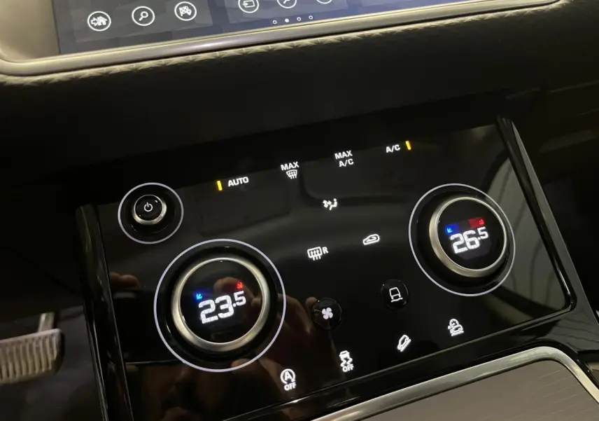 Gros plan sur la console centrale tactile du Range Rover Evoque 2020, affichant la climatisation bi-zone à 23,5°C et 26,5°C.