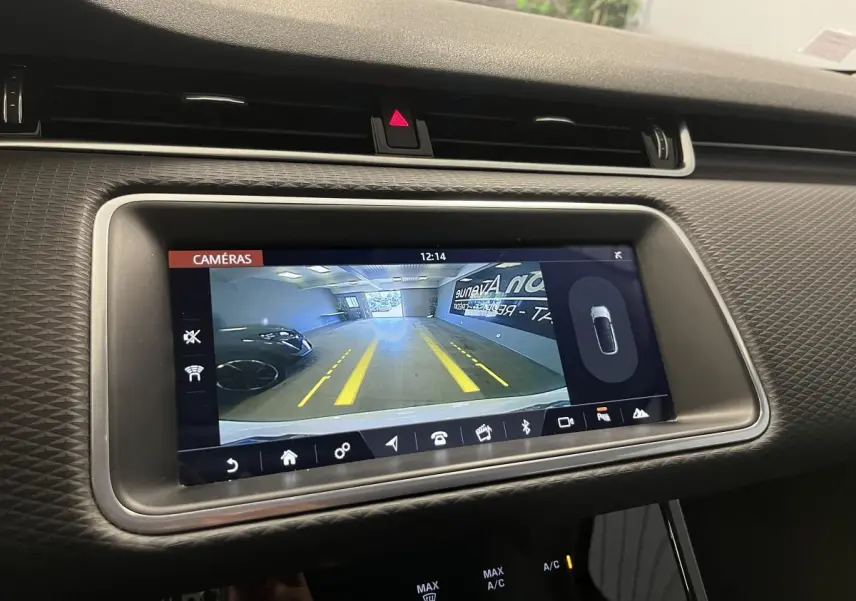 Écran tactile central montrant la caméra de recul du Range Rover Evoque blanc, avec lignes de guidage jaunes visibles.