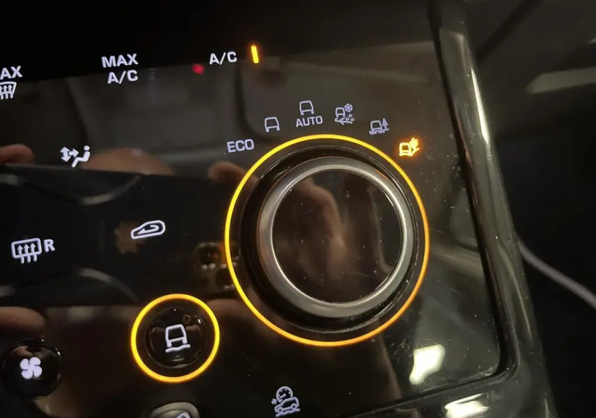 Gros plan sur la molette de sélection des modes de conduite du Range Rover Evoque blanc, éclairage orange autour.