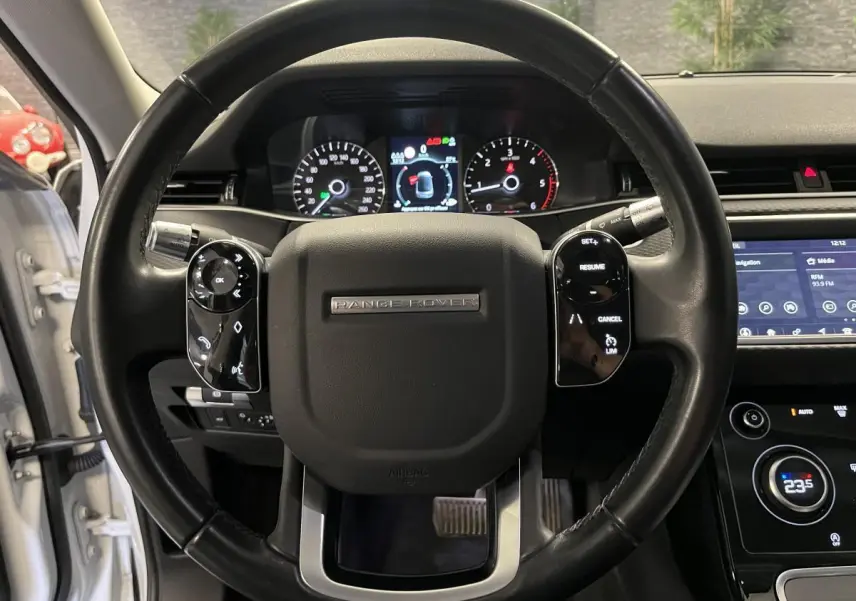 Vue rapprochée du volant noir de la Range Rover Evoque 2020 avec commandes intégrées et tableau de bord numérique.