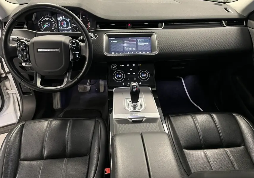 Vue intérieure avant du Range Rover Evoque 2020, sièges cuir noirs, tableau de bord avec écran tactile et volant multifonction.