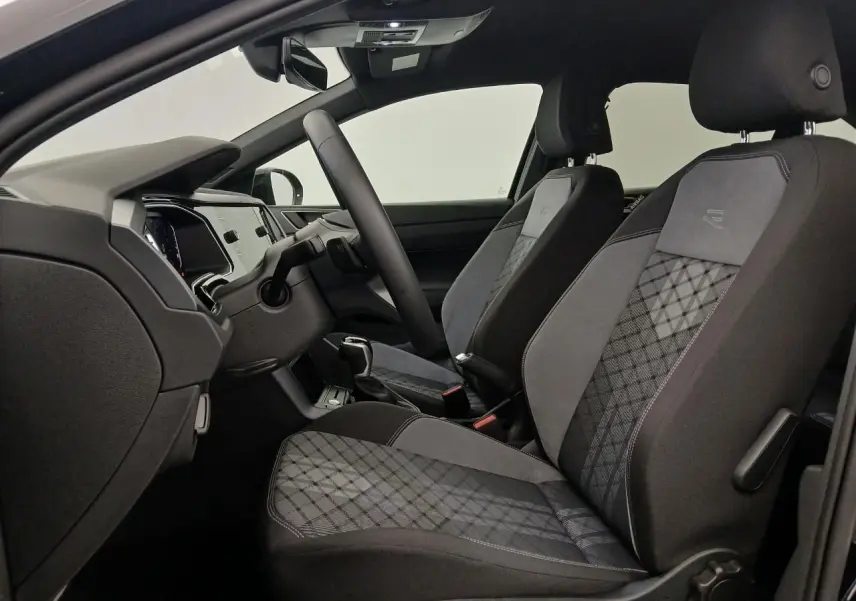 Vue intérieure côté gauche du Volkswagen Taigo R-Line 2025, sièges avant sport en tissu gris à motifs géométriques.