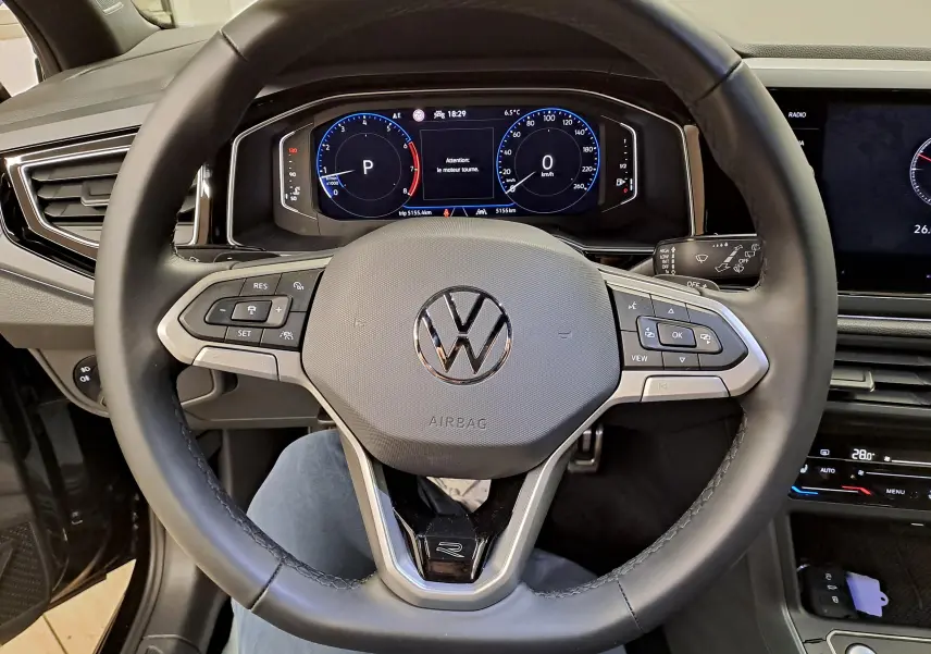 Vue rapprochée du volant cuir multifonctions avec logo VW et tableau de bord digital du Volkswagen Taigo 2025.