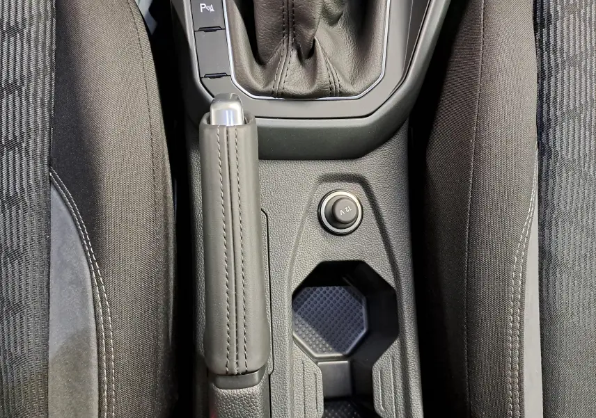 Vue plongeante sur la console centrale noire du Volkswagen Taigo 1.5 TSI R-Line avec frein à main cuir et prise 12V.