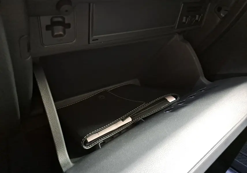 Gros plan sur la boîte à gants ouverte du Volkswagen Taigo 1.5 TSI 150 DSG7 R-Line Edition avec pochette noire à l'intérieur.