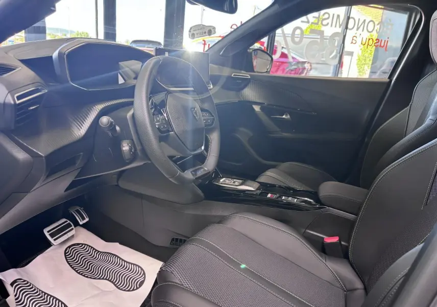 Intérieur de la Peugeot 2008 1.2i Hybrid GT 2026 vu côté conducteur, avec sellerie noire et volant compact cuir.