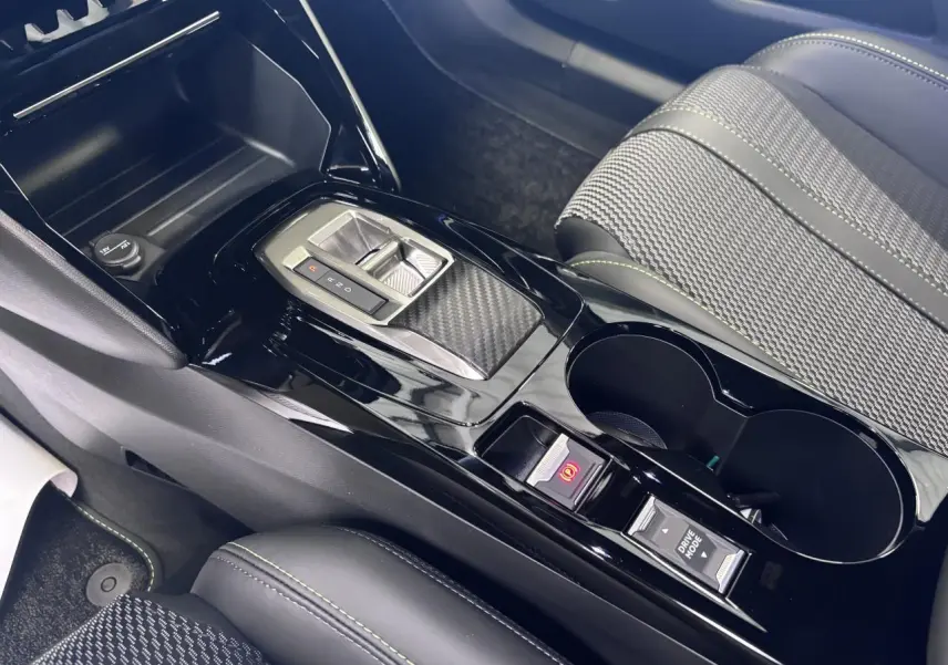 Vue rapprochée de la console centrale noire brillante avec levier de vitesse et siège tissu gris avec surpiqûres vertes Peugeot 2008.