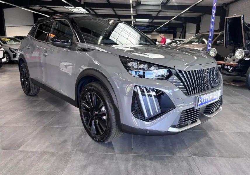 Peugeot 2008 gris selenium en 3/4 avant droit avec jantes noires bi-tons et calandre noire distinctive.