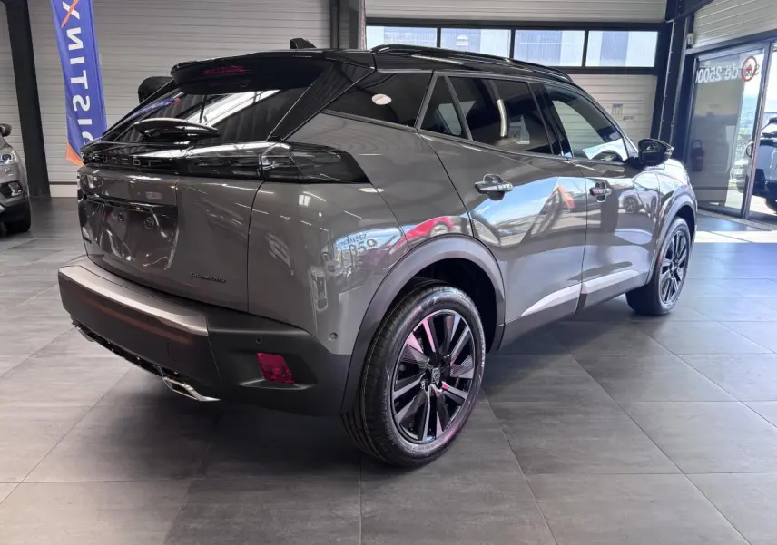 Peugeot 2008 gris selenium en 3/4 arrière droit, jantes alliage bi-ton noir et toit noir brillant visible en showroom.
