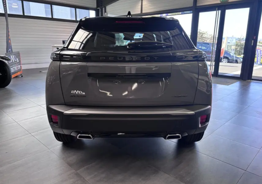 Vue arrière du Peugeot 2008 gris selenium avec double sortie d’échappement chromée et toit noir brillant en showroom.