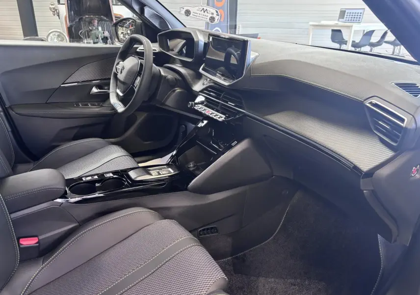 Vue intérieure côté conducteur du Peugeot 2008 1.2i Hybrid 145 GT, avec sellerie tissu et console centrale noire brillante.