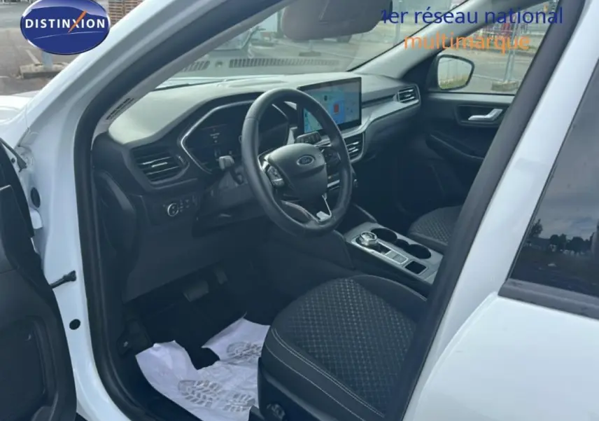 Vue intérieure côté conducteur du Ford Kuga blanc 2025, avec tableau de bord numérique et écran tactile central.
