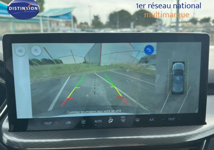 Écran central montrant la caméra de recul du Ford Kuga blanc, avec lignes de guidage colorées et vue 360° du véhicule.