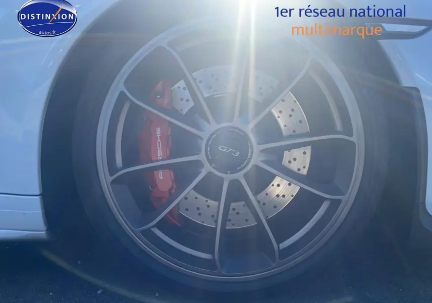 Gros plan sur la roue arrière droite blanche d'une Porsche 911 (991) GT3 avec étrier de frein rouge et jante noire.