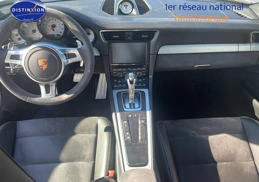 Vue intérieure de face du tableau de bord et console centrale d'une Porsche 911 GT3 991 avec volant cuir et sièges sport noirs.