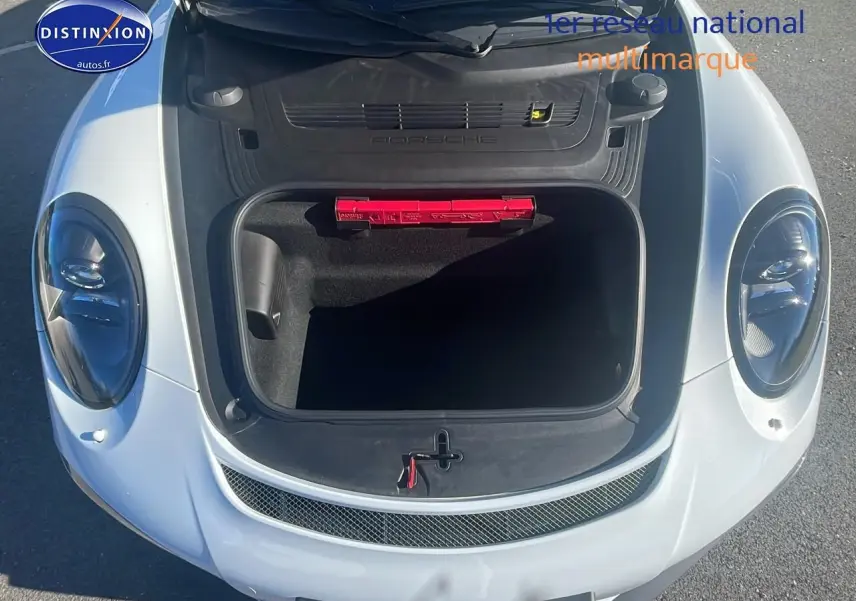 Vue plongeante sur le coffre avant ouvert d'une Porsche 911 GT3 blanche, avec trousse de secours rouge visible.