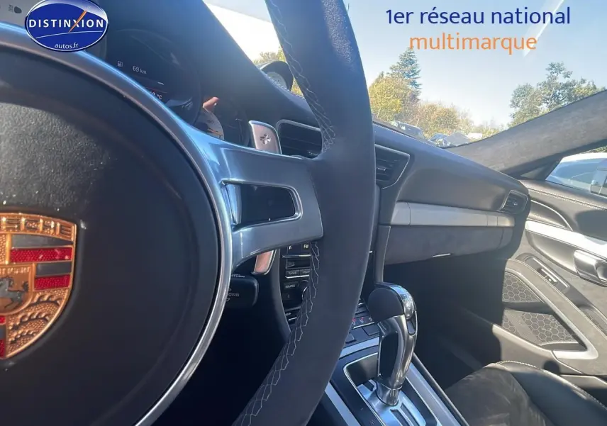 Intérieur de Porsche 911 GT3 blanc, vue côté conducteur sur volant sport, tableau de bord et levier de vitesse automatique.