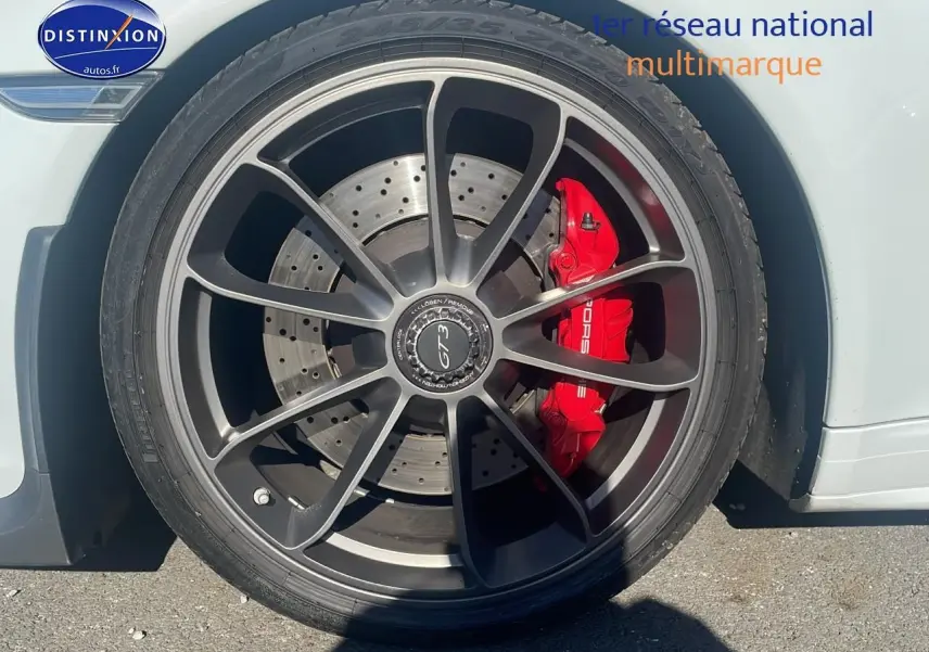 Gros plan sur la roue avant droite blanche d'une Porsche 911 (991) GT3 avec étrier de frein rouge et jante alu noire.