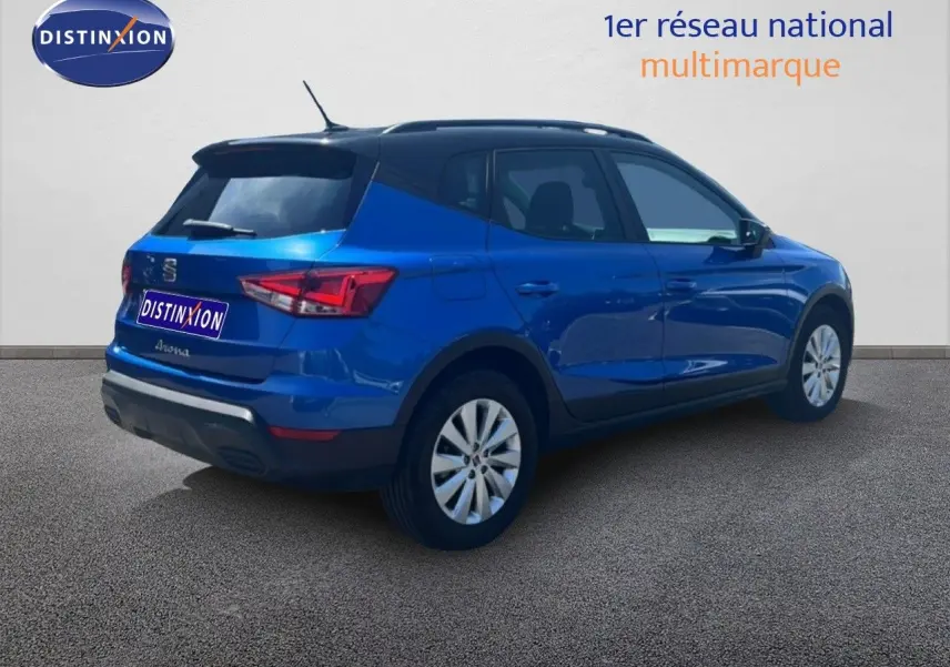 Vue 3/4 arrière droite d'un SEAT Arona bleu saphir métallisé avec toit noir, sur fond neutre extérieur.
