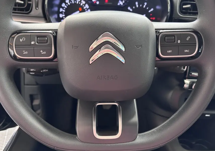 Gros plan sur le volant multifonctions noir de la Citroën C3 PureTech 110 BVM6 PLUS avec logo chromé central.