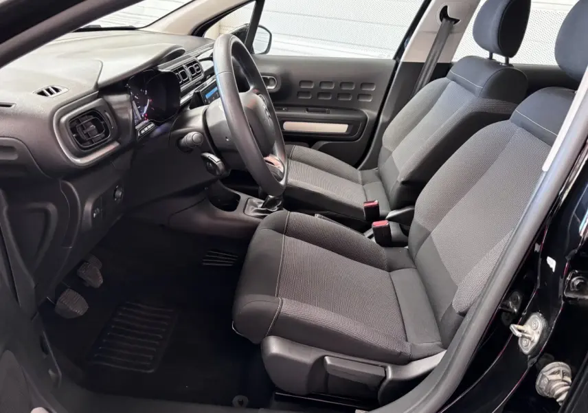 Vue intérieure côté conducteur de la Citroën C3 PureTech 110 noire, montrant sièges tissu et tableau de bord moderne.