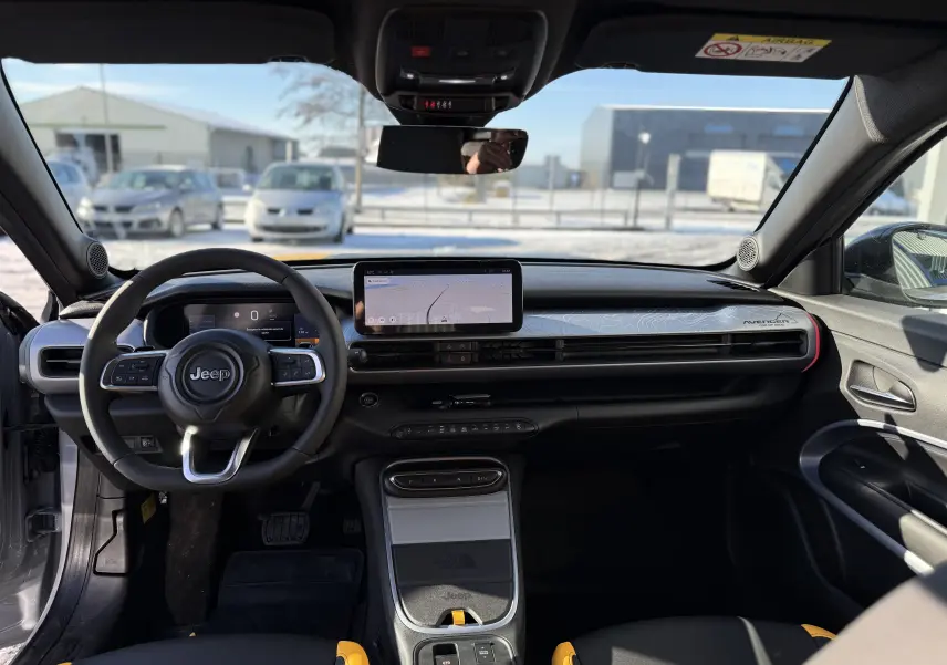 Vue intérieure avant du Jeep Avenger Storm Grey 2025, tableau de bord moderne avec écran tactile et détails jaunes sur sièges.