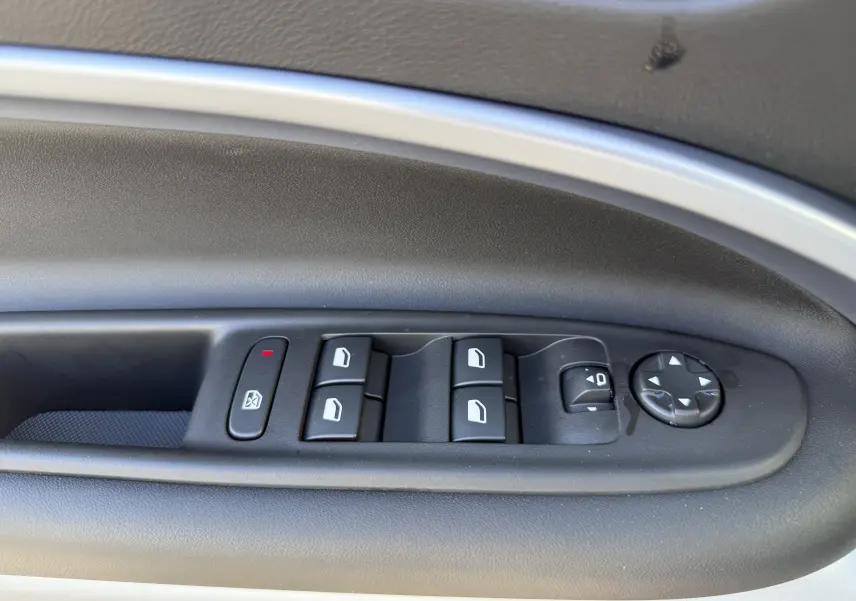 Gros plan sur les commandes de lève-vitres et réglage des rétroviseurs côté gauche intérieur du Jeep Avenger Storm Grey.