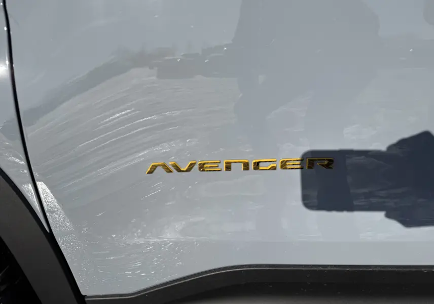 Gros plan sur l’inscription dorée Avenger sur la portière côté gauche d’un Jeep Avenger Storm Grey.