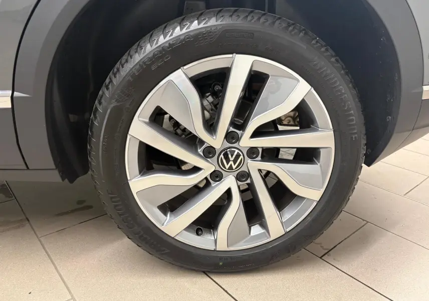 Gros plan sur la roue avant droite du Volkswagen T-Roc 2025 gris Indium avec jante alliage et pneu Bridgestone.