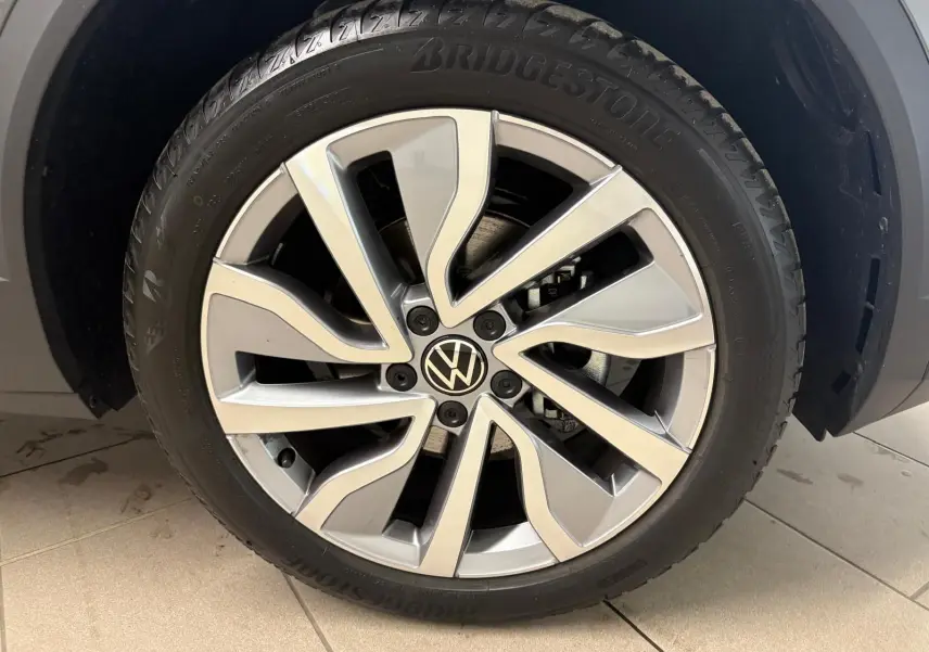 Gros plan sur la roue avant droite du Volkswagen T-Roc 2025 gris Indium avec jante alliage et pneu Bridgestone.