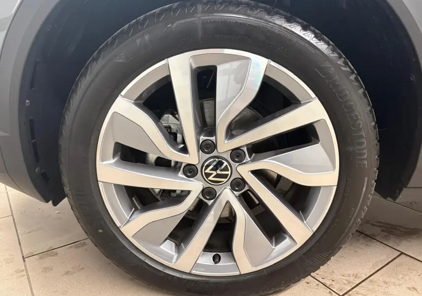 Gros plan sur la jante alliage du Volkswagen T-Roc 2025 en Gris Indium, avec pneu Bridgestone visible.