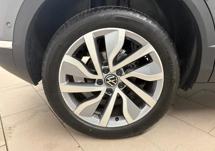 Gros plan sur la roue avant droite du Volkswagen T-Roc 2025 gris Indium avec jante alliage distinctive.