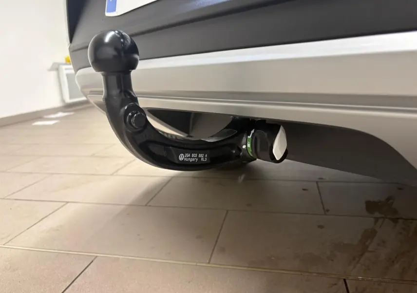 Gros plan sur l'attelage amovible noir sous le pare-chocs arrière d'un Volkswagen T-Roc gris Indium.