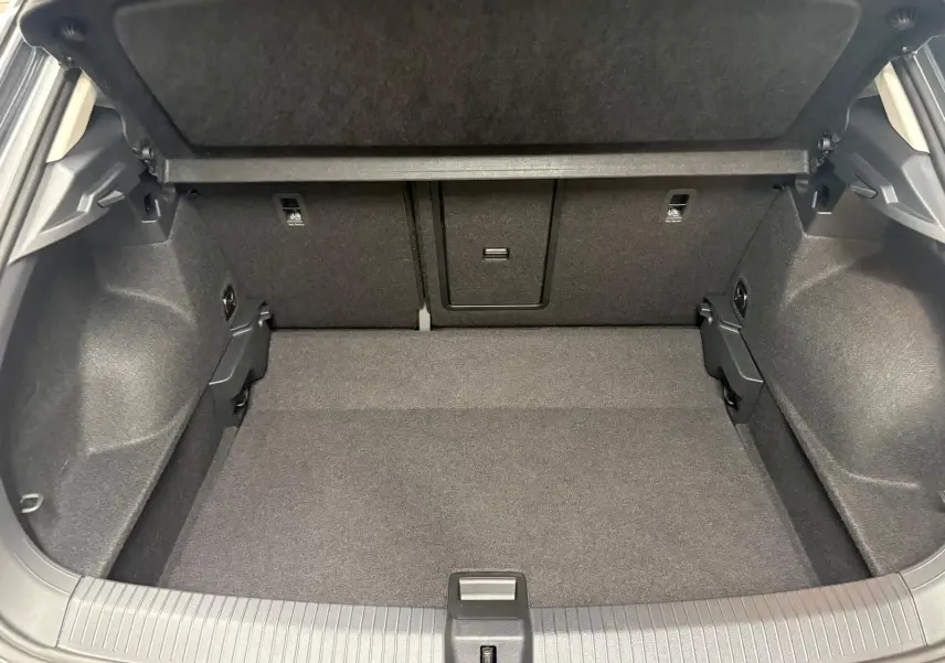 Vue intérieure du coffre spacieux et propre du Volkswagen T-Roc 2025, avec habillage noir uniforme et banquette arrière rabattable.