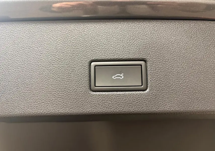 Bouton d'ouverture électrique du coffre sur la garniture intérieure d'un Volkswagen T-Roc Gris Indium 2025.