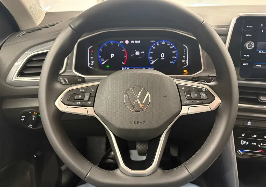 Vue intérieure centrée sur le volant multifonction et le tableau de bord numérique du Volkswagen T-Roc 2025.