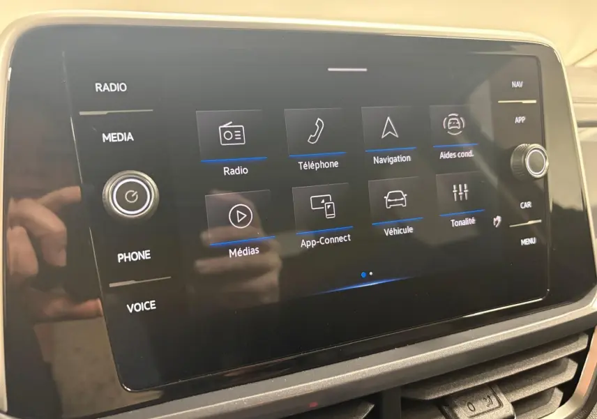 Écran tactile central du Volkswagen T-Roc 2025 affichant les options radio, téléphone, navigation et aides à la conduite.