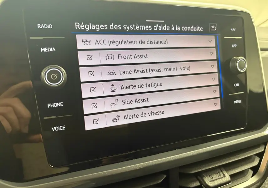 Écran tactile du tableau de bord du Volkswagen T-Roc 2025 affichant les réglages des aides à la conduite.