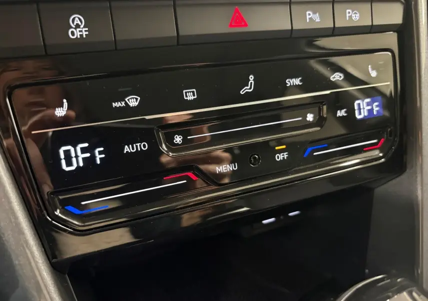 Gros plan sur la commande de climatisation digitale du Volkswagen T-Roc 2025 en finition Style Exclusive, intérieur noir brillant.