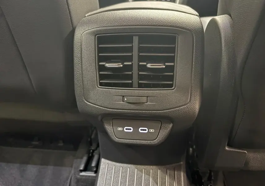 Vue rapprochée de la console arrière du Volkswagen T-Roc gris Indium, avec bouches d’aération et ports USB visibles.
