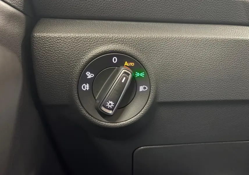 Gros plan sur le sélecteur de phares du tableau de bord noir du Volkswagen T-Roc 2025, avec éclairage automatique activé.