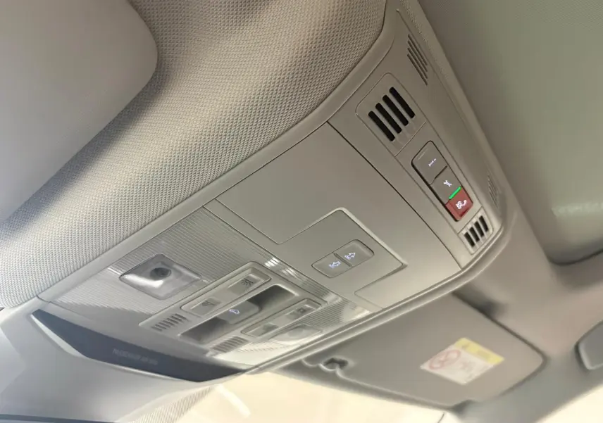 Vue intérieure du plafonnier gris clair du Volkswagen T-Roc 2025 avec commandes d'éclairage et toit ouvrant.