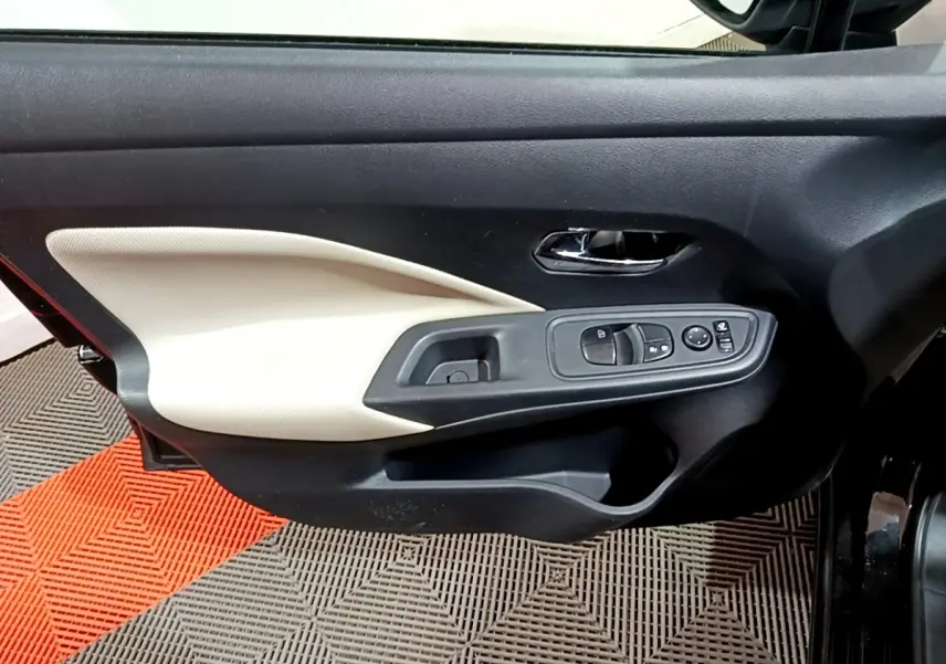 Vue intérieure côté gauche de la porte avant noire de la Nissan Micra IG-T 90 N-Connecta avec panneau beige et commandes électriques.