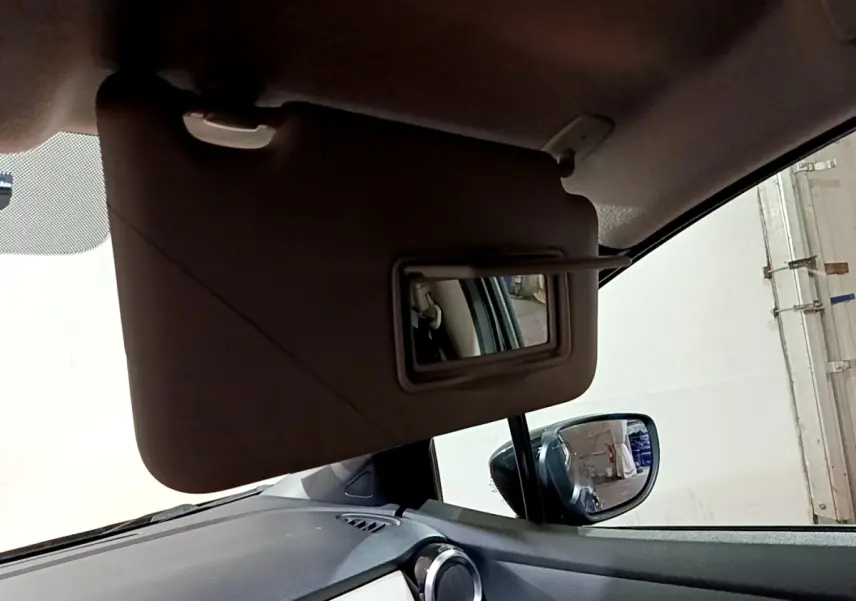 Vue intérieure rapprochée du pare-soleil avec miroir ouvert côté conducteur d'une Nissan Micra noire de 2017.