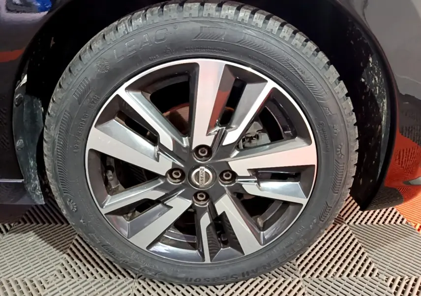 Gros plan sur la roue avant droite d’une Nissan Micra noire, avec jante alliage au design moderne bicolore.