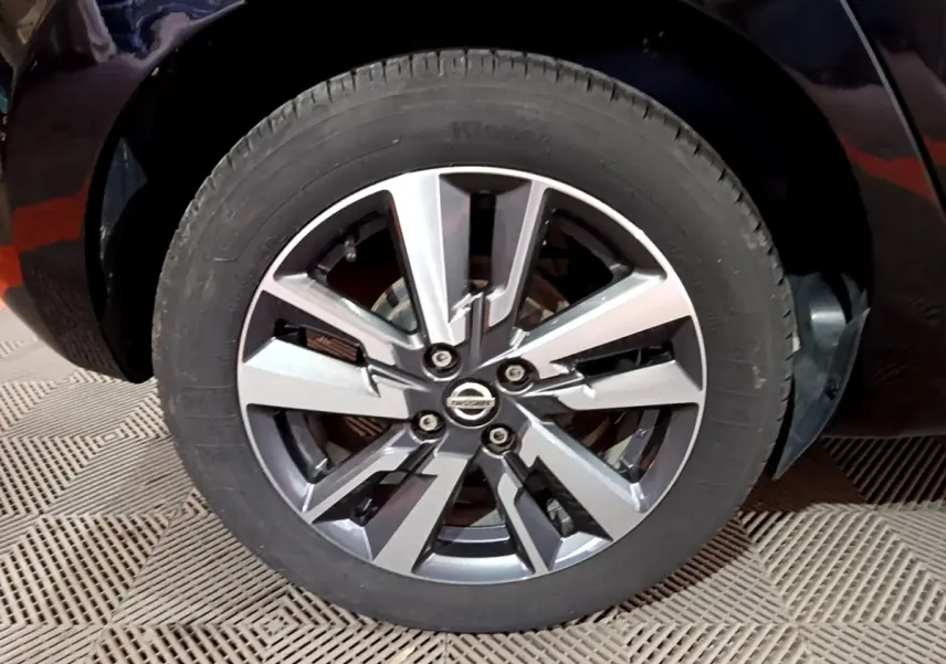 Gros plan sur la roue avant droite d’une Nissan Micra noire, mettant en valeur la jante alliage au design moderne.